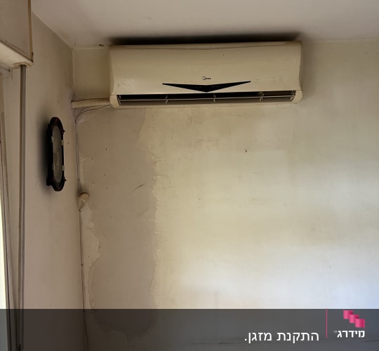 מזגן מותקן על קיר בחדר עם קיר מתקלף